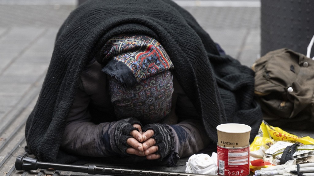 Eine Bettlerin bittet in einer Fußgängerzone um Geld