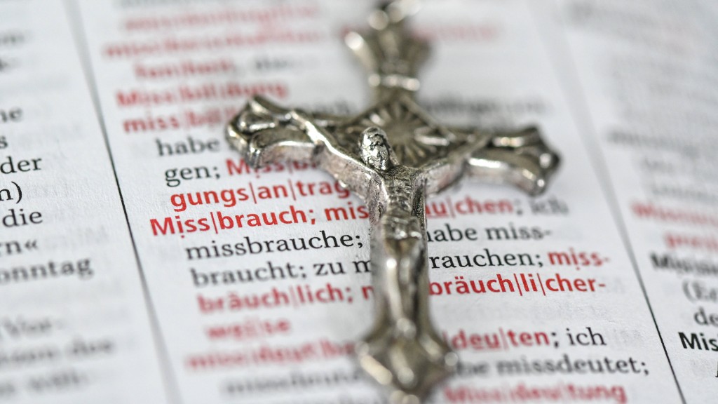 Ein Kreuz liegt auf einer Seite eines Wörterbuchs, auf der das Wort Missbrauch zu lesen ist