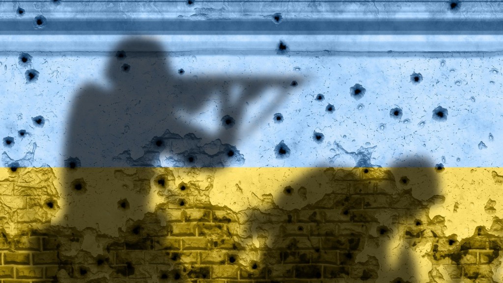 Die Silhouetten von Soldaten vor einer blau-gelben Mauer, die von Schüssen getroffen worden ist