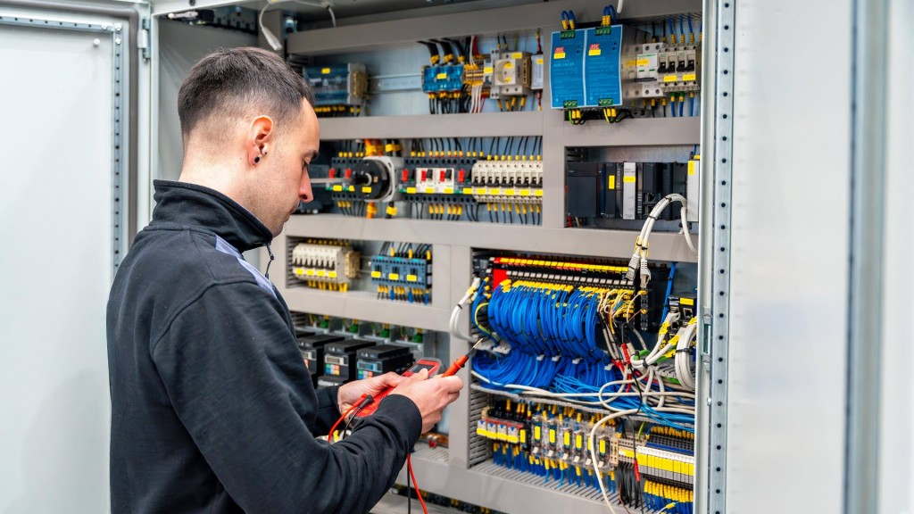 Arbeiter, der ein elektrisches mechanisches System in einer Fabrik repariert. 