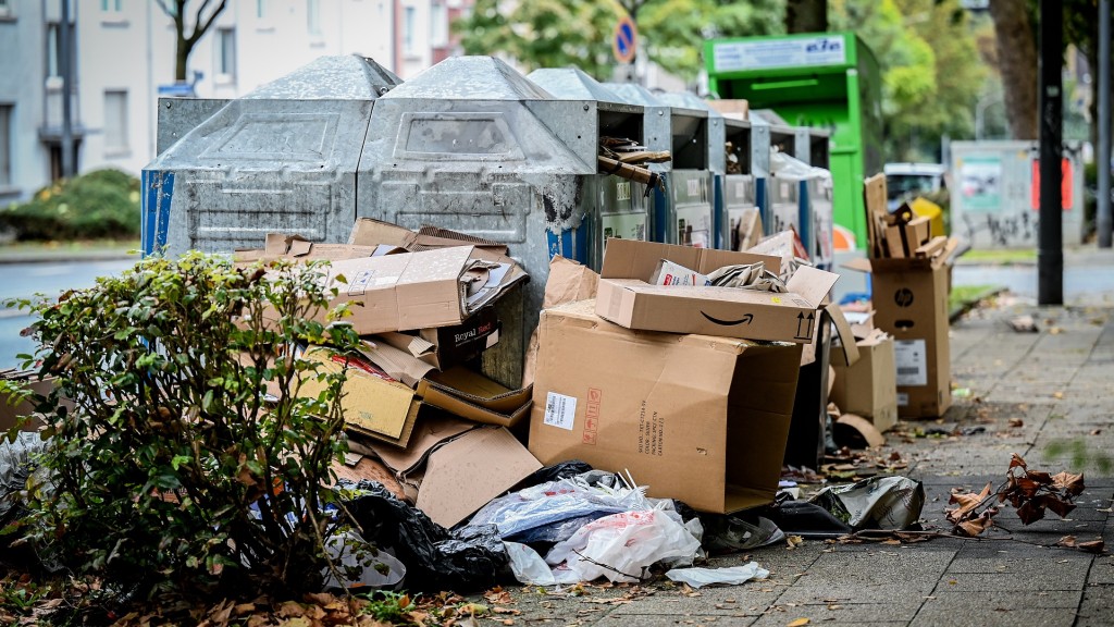 Pappkartons und Müll liegen vor vollen Altpapiercontainern.