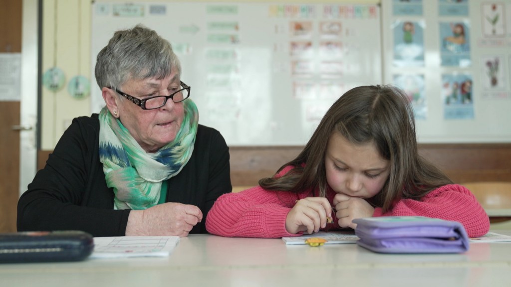 Foto: Frau hilft Kind bei Schulaufgaben