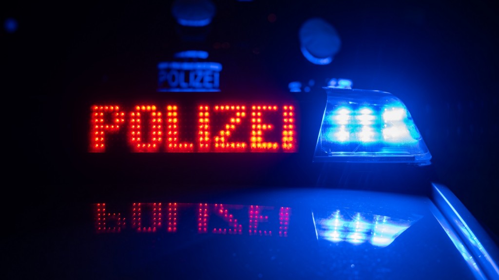 Polizisten stehen nachts vor einem Polizeifahrzeug 