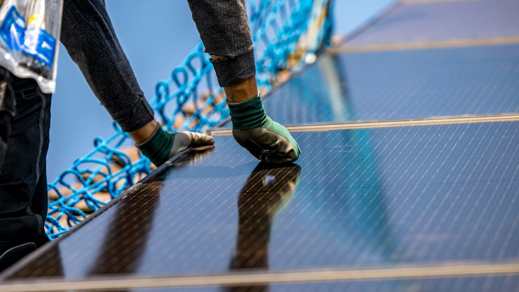 Foto: Solarenergie: Arbeiter installieren eine Photovoltaikanlage auf dem Dach eines Gebäudes