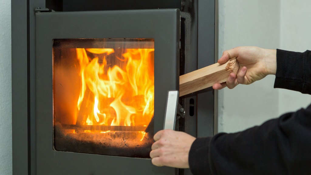 Ein Mann legt ein Stück Holz auf das Feuer im Kaminofen