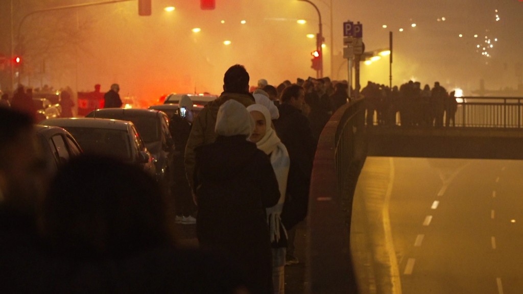 Foto: Menschen stehen in der SIlvesternacht auf einer Brücke 