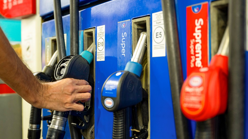 Ein Autofahrer hängt an einer Tankstelle eine Zapfpistole zurück