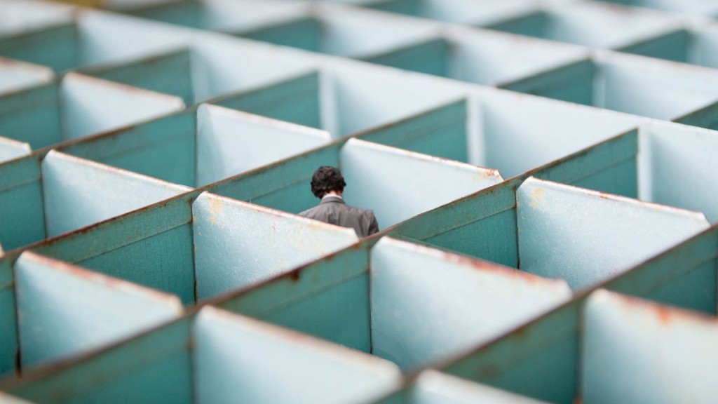 Ein Mann in einem grauen Anzug, der sich in den Weiten eines Labyrinths verlaufen hat