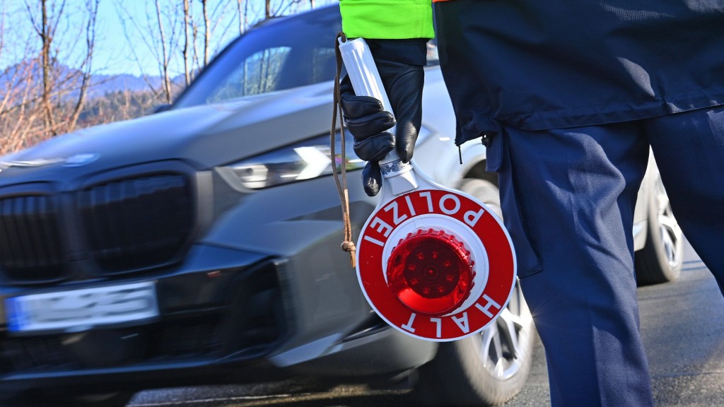 Grenzkontrolle der Polizei. Beamter mit einer Polizeikelle steht neben einem Fahrzeug.