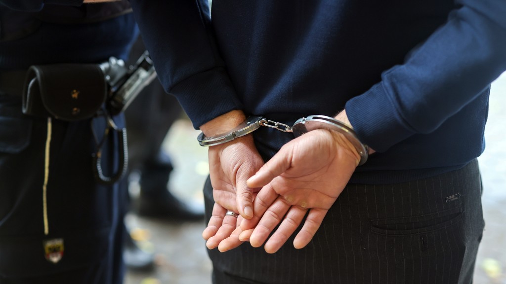 Ein Polizist führt einen Mann mit Handschellen ab