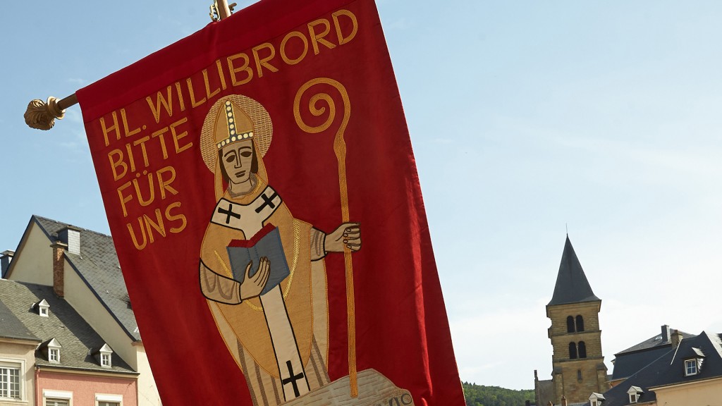 Missionar Willibrord auf einem Banner bei einer Springprozession in Luxemburg