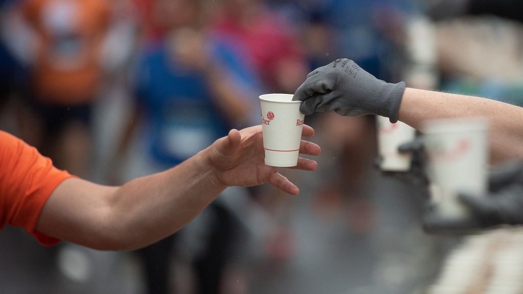 LäuferEin Läufer nimmt während des Firmenlaufs einen Einweg-Becher mit Wasser von einem Helfer entgegen
