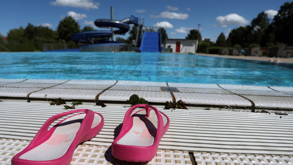Flip Flops stehen am Beckenrand des Nichtschwimmerbeckens eines Freibades.