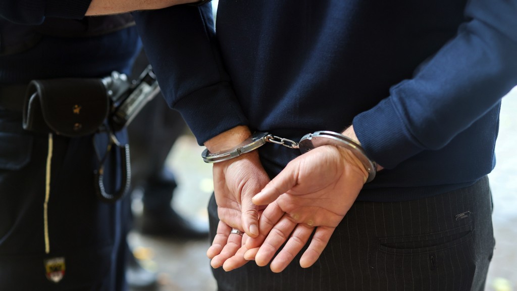 Ein Polizist führt einen Mann mit Handschellen ab