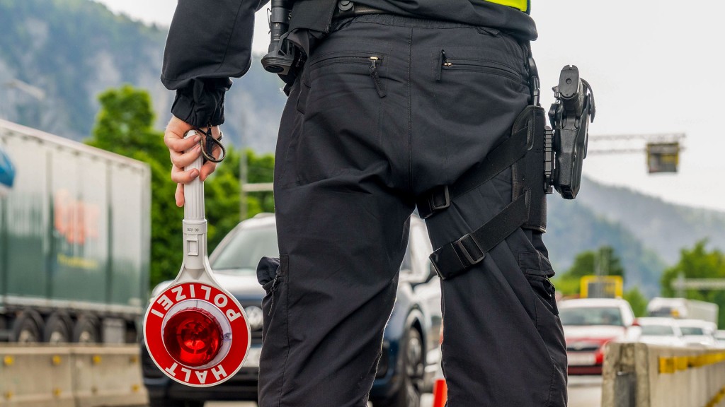 Ein Polizist hält eine Anhaltekelle bei einer Grenzkontrolle