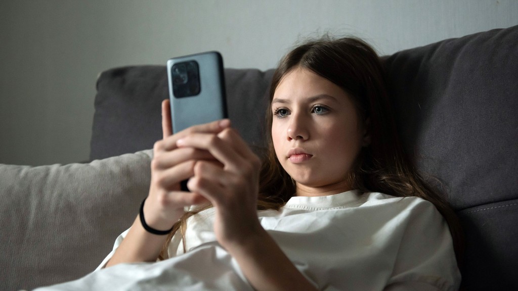 Foto: Ein Kind sitzt mit Smartphone auf der Couch