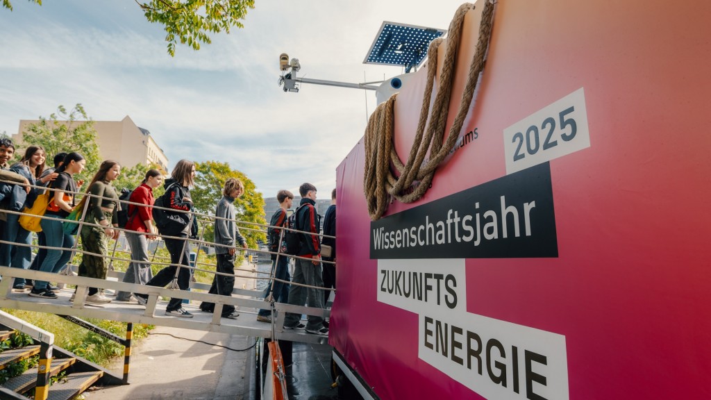 Foto: Außenaufnahme der MS Wissenschaft 2025. Jugendliche besteigen das umgebaute Frachtschiff.