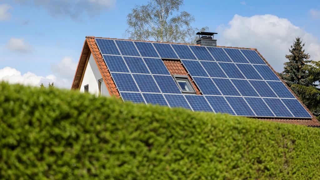 Foto: Ein Einfamilienhaus mit Solarpaneelen auf dem Hausdach steht hinter einer grünen Hecke.