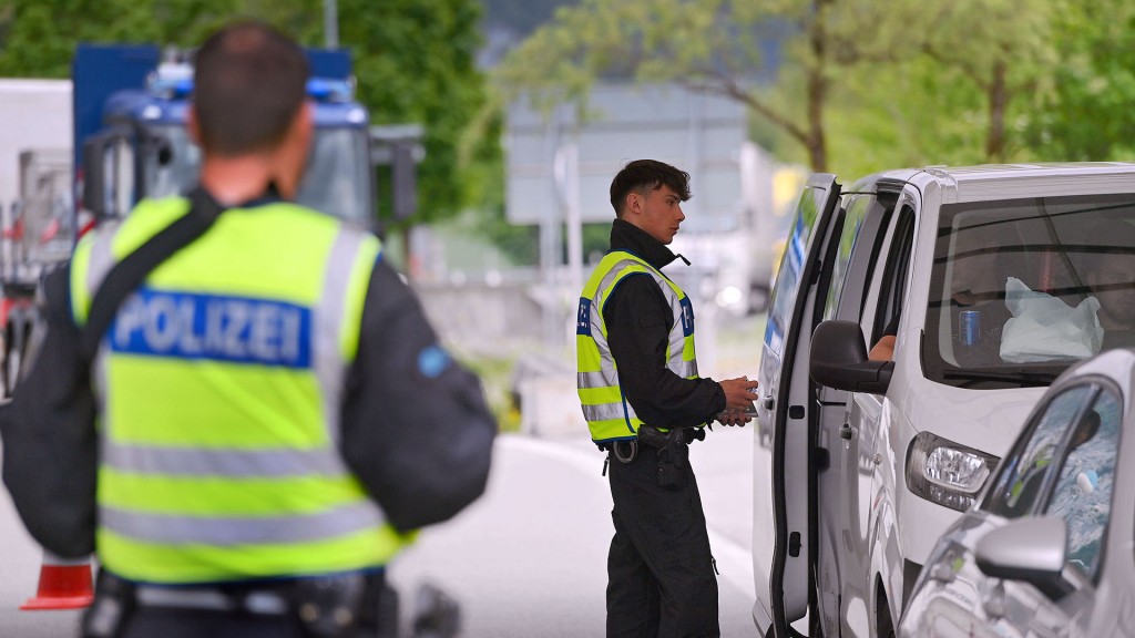 Polizisten kontrollieren Fahrzeuge an einem Grenzübergang