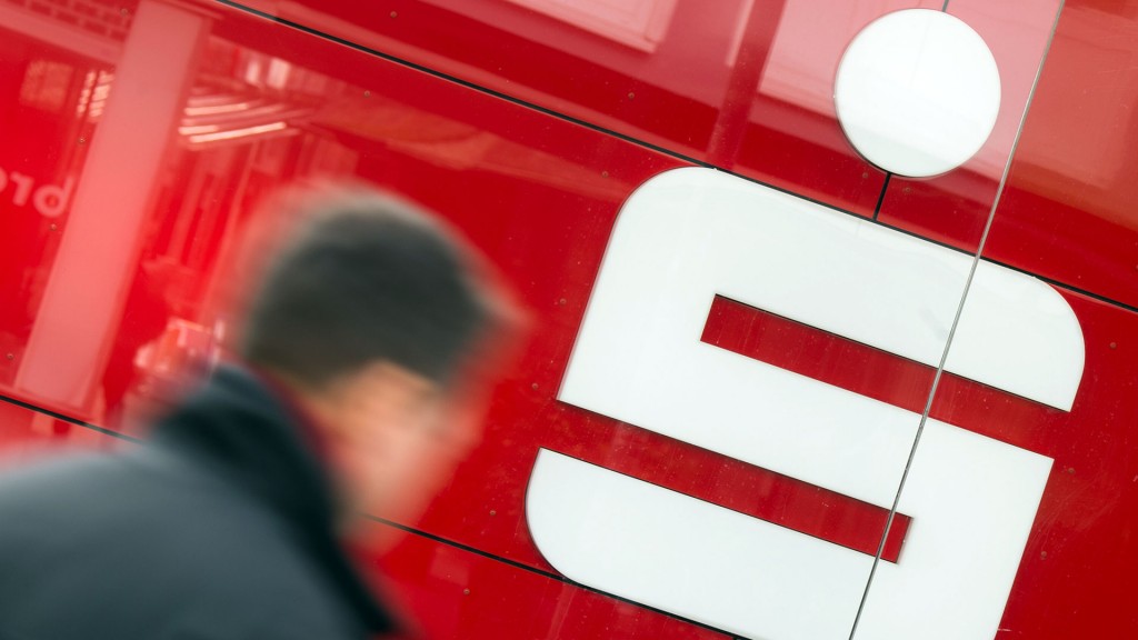 Foto: Jemand geht vor einem Logo der Sparkasse vorbei