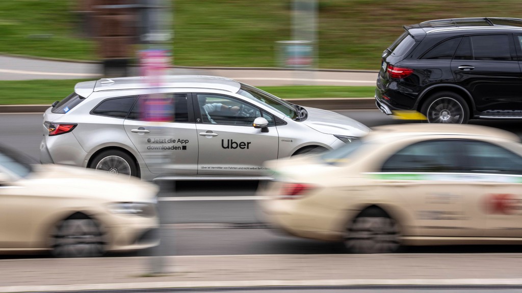 Ein Uber-Mietwagen fährt an Taxen vorbei