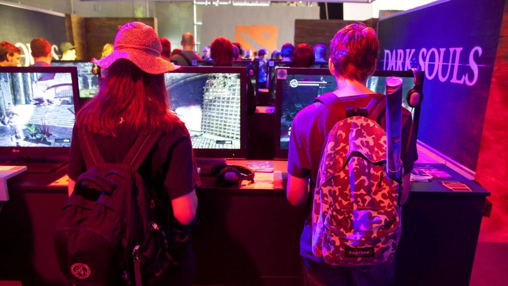 Jugendliche Messebesucher spielen an einem Messestand das Computerspiel Dark Souls.