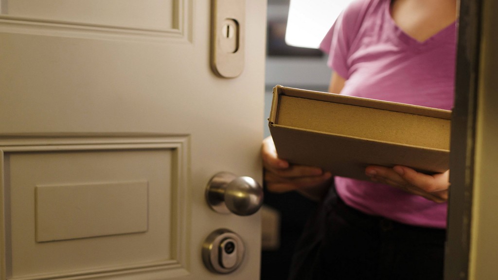 Eine Frau hält ein Paket hinter der Haustür in der Hand