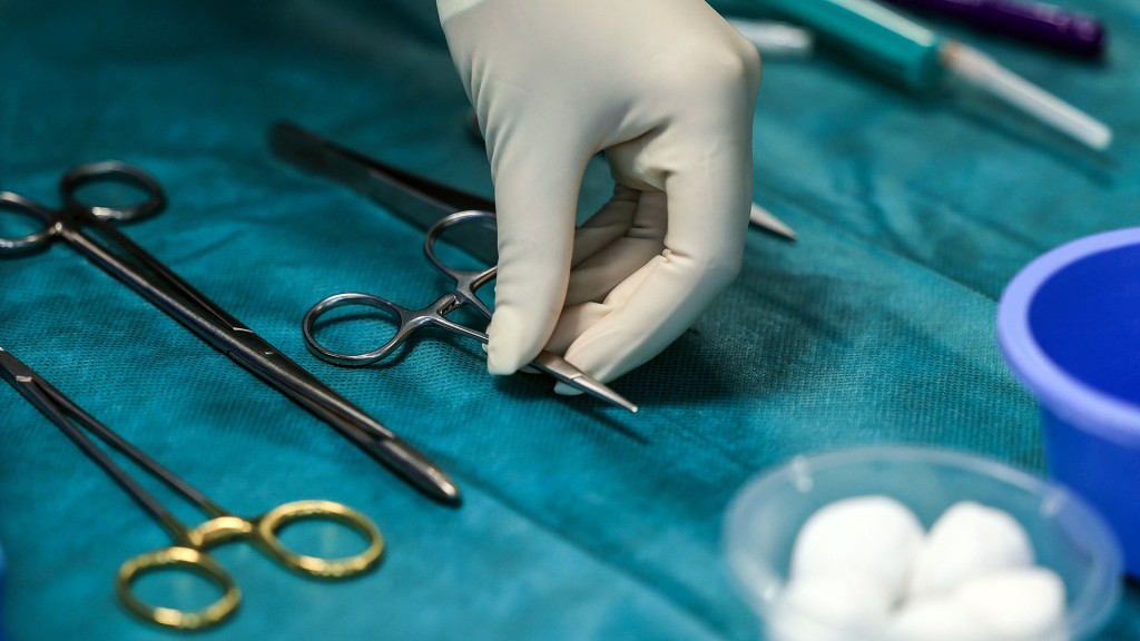 Eine Hand greift nach einer Klemme im Operationssaal