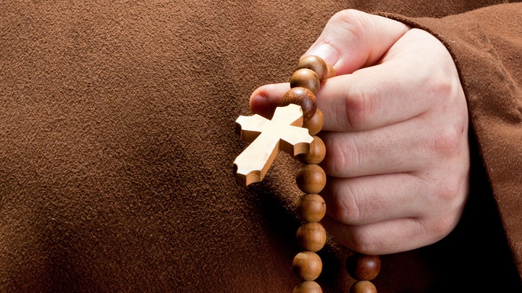Ein Mann hält einen Rosenkranz in der Hand