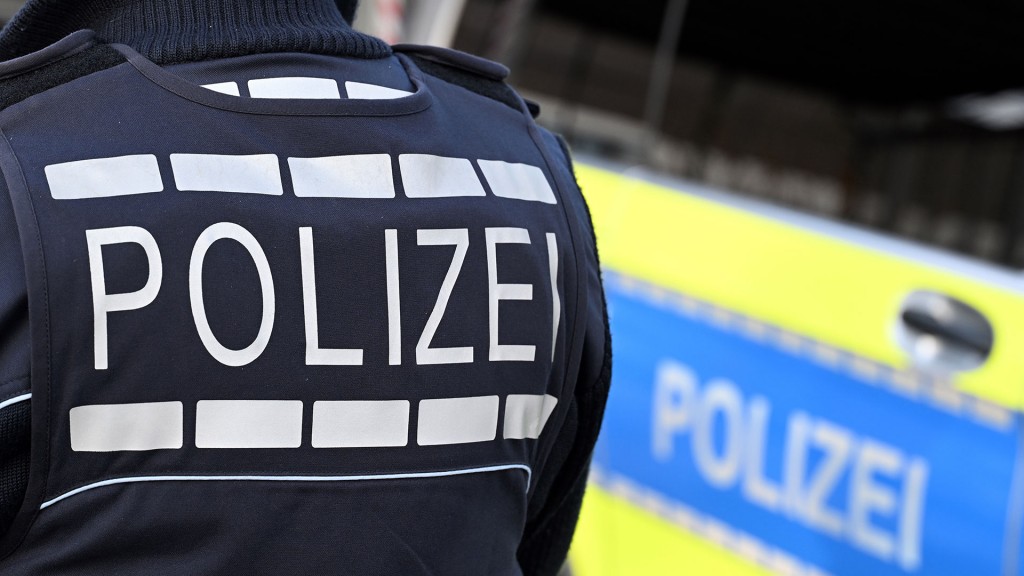 Ein Polizist steht neben einem Einsatzfahrzeug