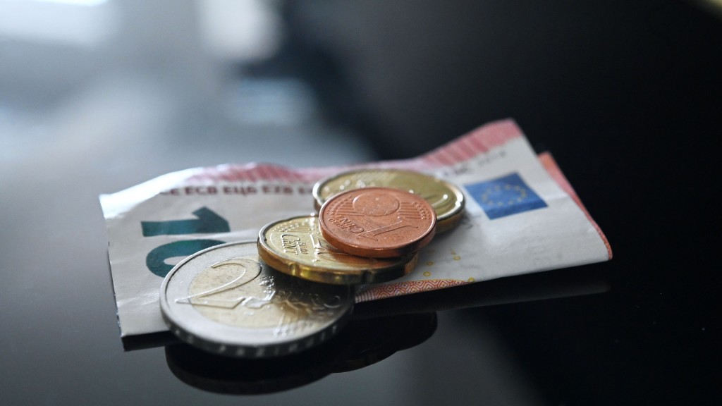 Foto: Münzen und ein Geldschein liegen auf einer schwarzen Fläche.