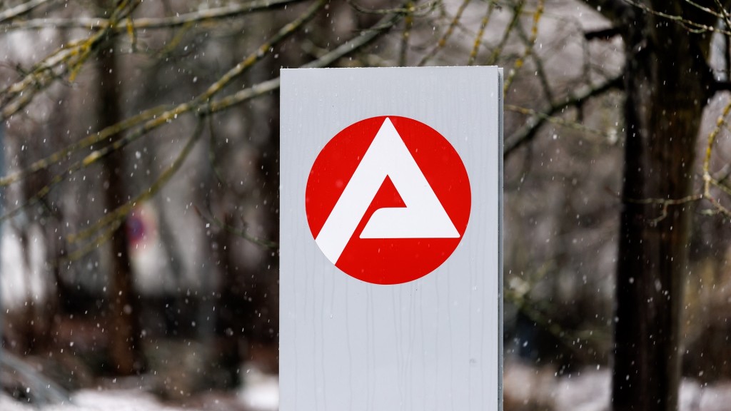 Das Logo der Agentur für Arbeit auf einer Stele bei winterlichem Wetter.