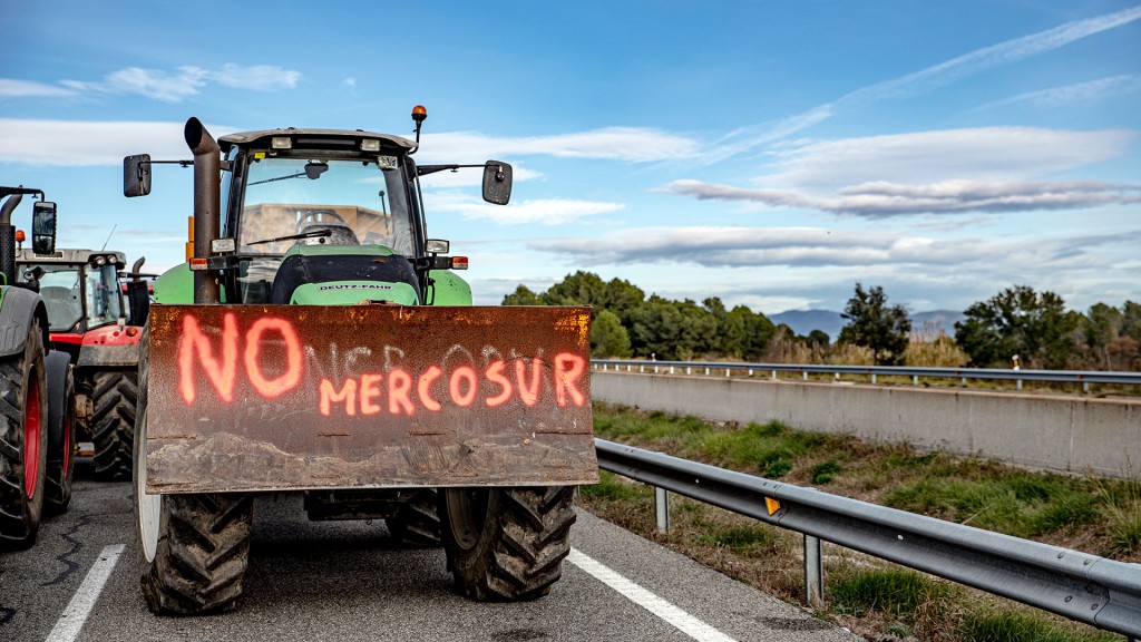 Ein Traktor steht zum Protest auf der Landstraße mit einem Graffiti gegen das Mercosur-Abkommen