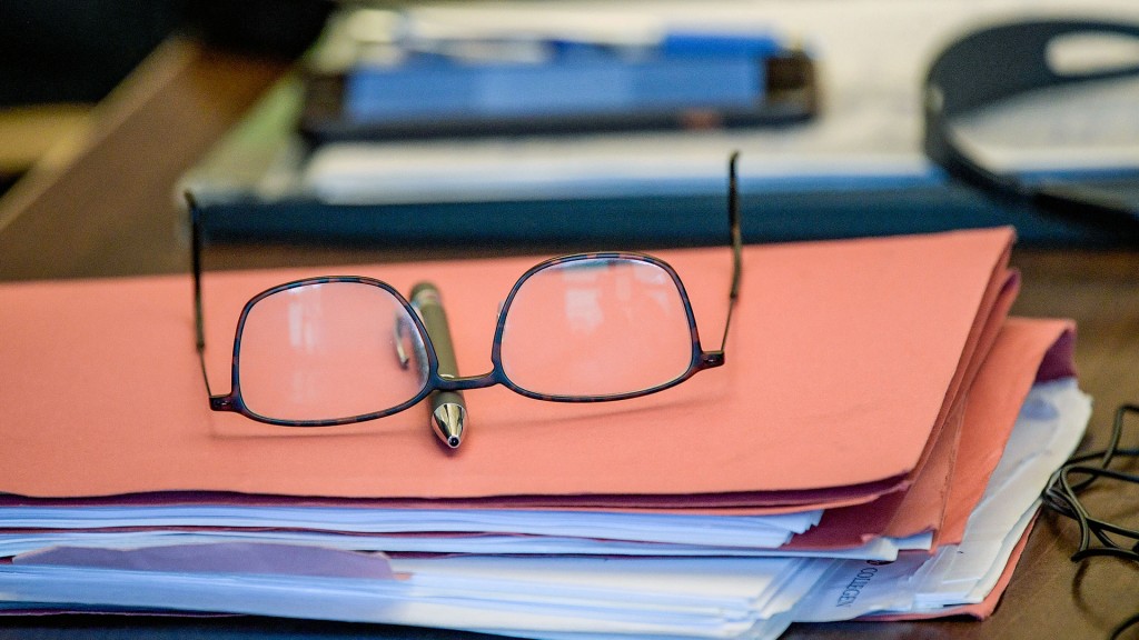 Eine Brille liegt auf einer Aktenmappe mit einigen Unterlagen