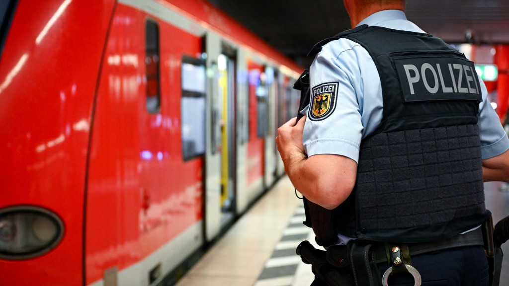 Foto: Ein Bundespolizist steht am Gleis vor einer Regionalbahn