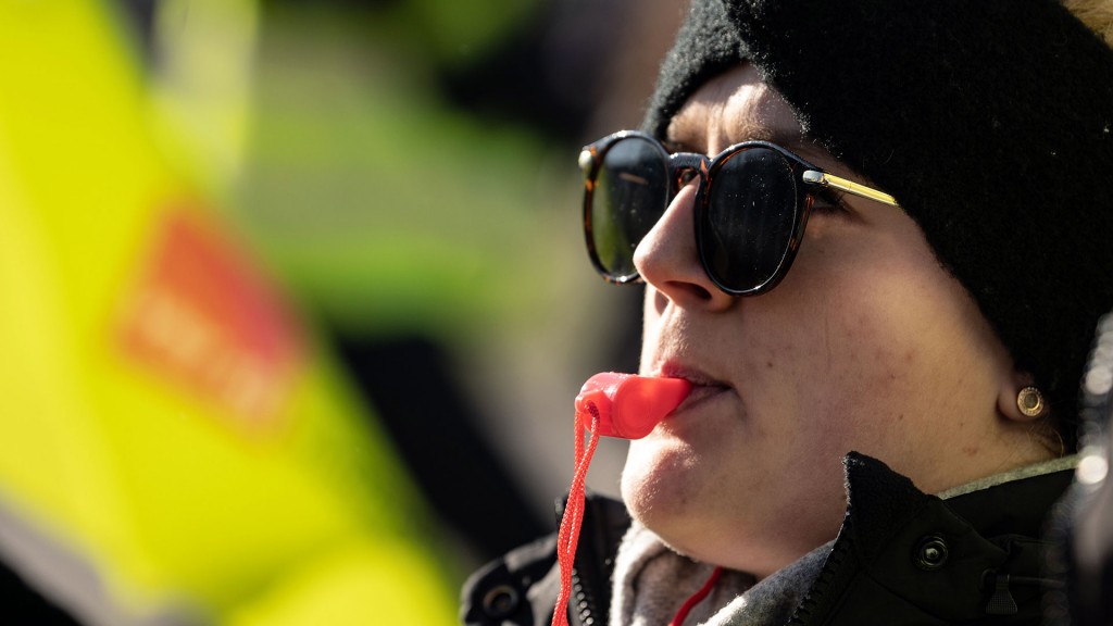 Foto: Frau mit Sonnenbrille und roter Trillerpfeife