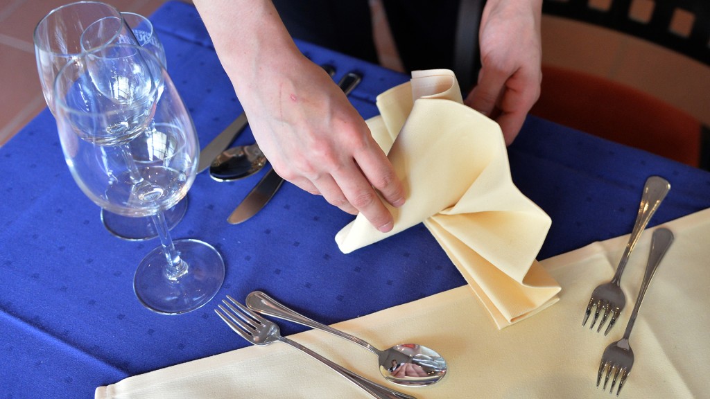 Eine Hotelfachangestellte stellt eine Serviette auf einen Tisch. 