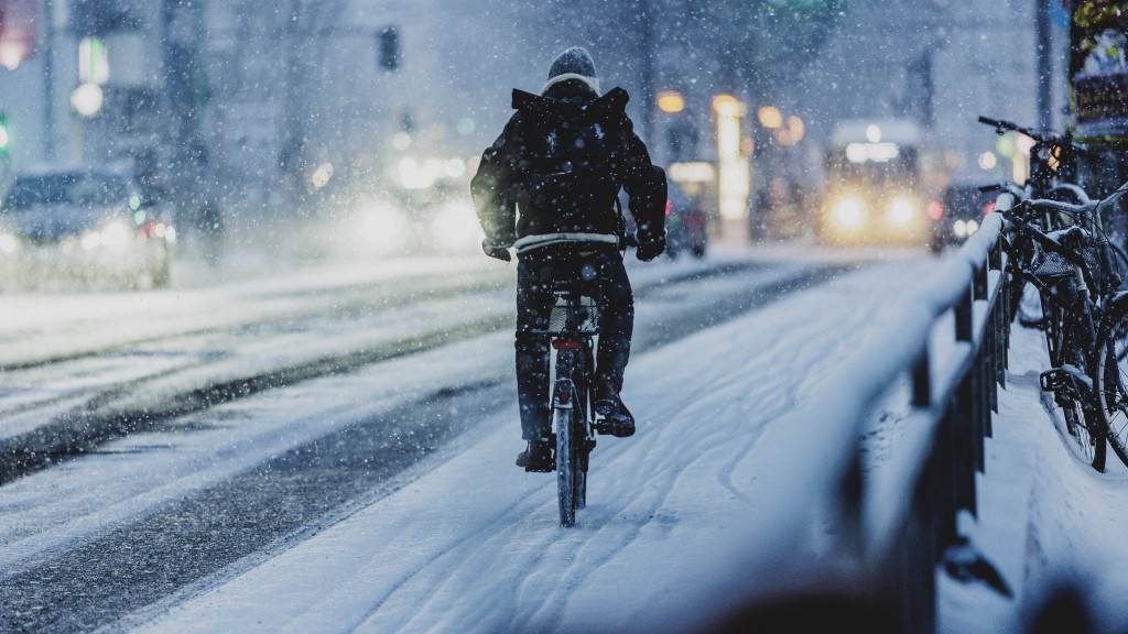 Eine Person mit Fahrrad auf einem mit Schnee bedecktem Radweg