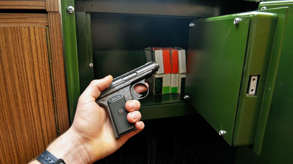 Jemand hält eine kleine Handfeuerwaffe vor einem Tresor für die sichere Aufbewahrung