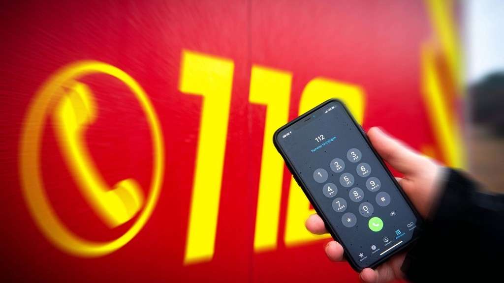 Die Notrufnummer 112 auf einem Smartphone vor einem Feuerwehrwagen