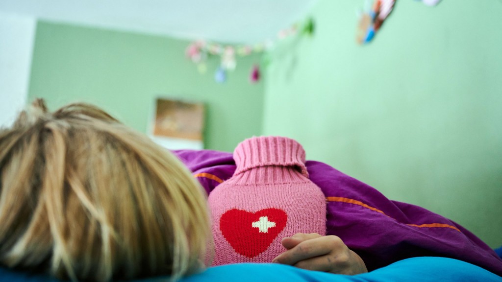 Ein krankes Kind liegt mit Wärmflasche im Bett