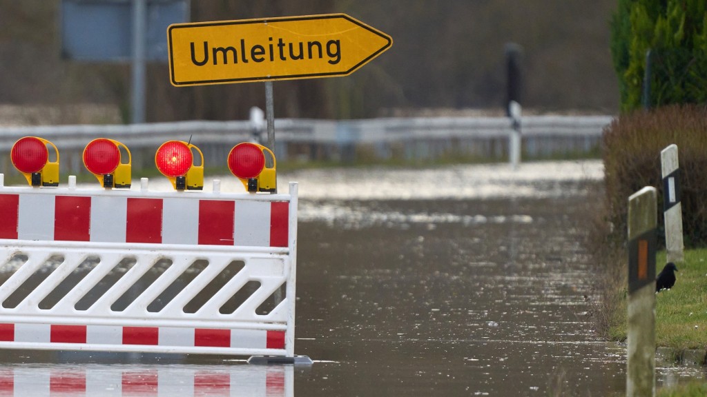 Hochwasser. Straßensperre und ein Umleitungsschild in einer überfluteten Straße.