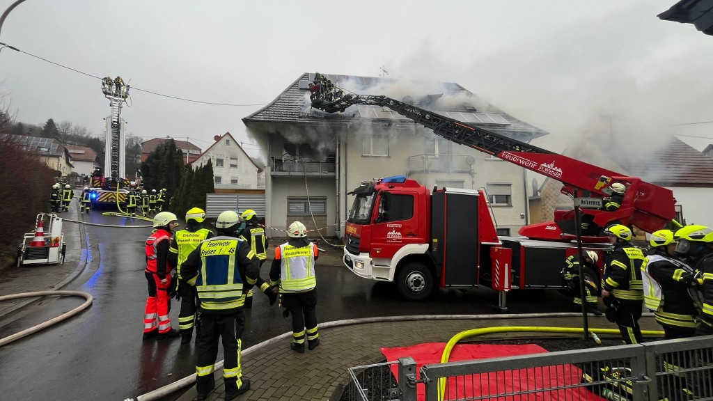 Symbolbild Feuerwehr. Ein Feuerwehrmann steht vor dem Einsatzwagen.