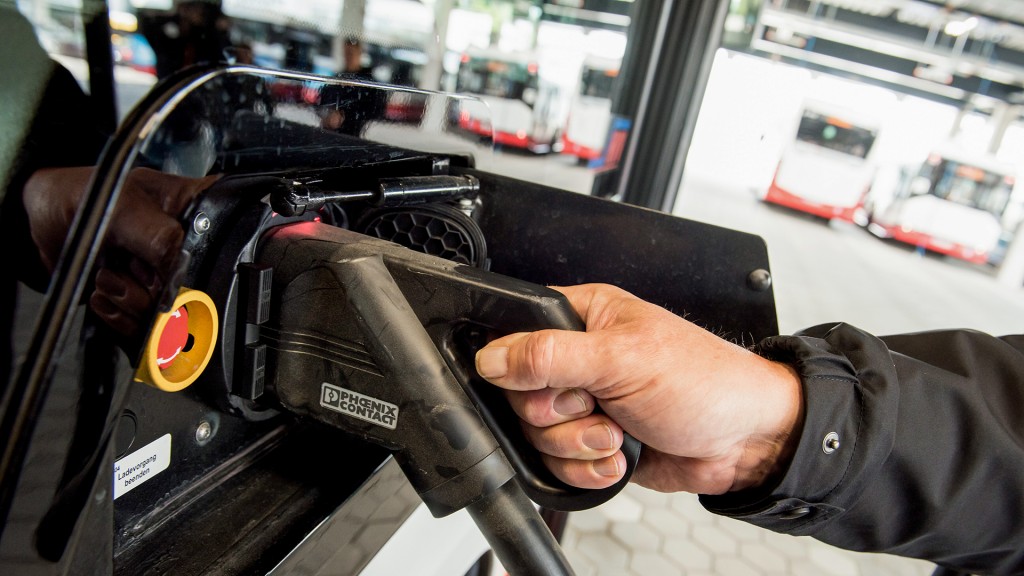 Foto: Ein Busfahrer schließt ein Ladekabel an einen Elektrobus