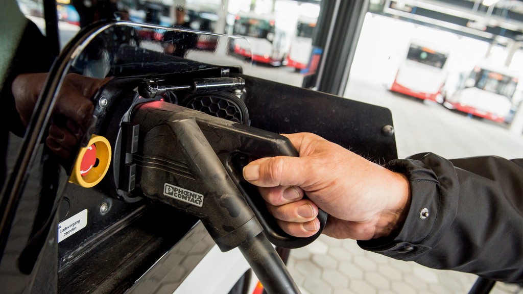 Ein Busfahrer schließt ein Ladekabel an einen Elektrobus