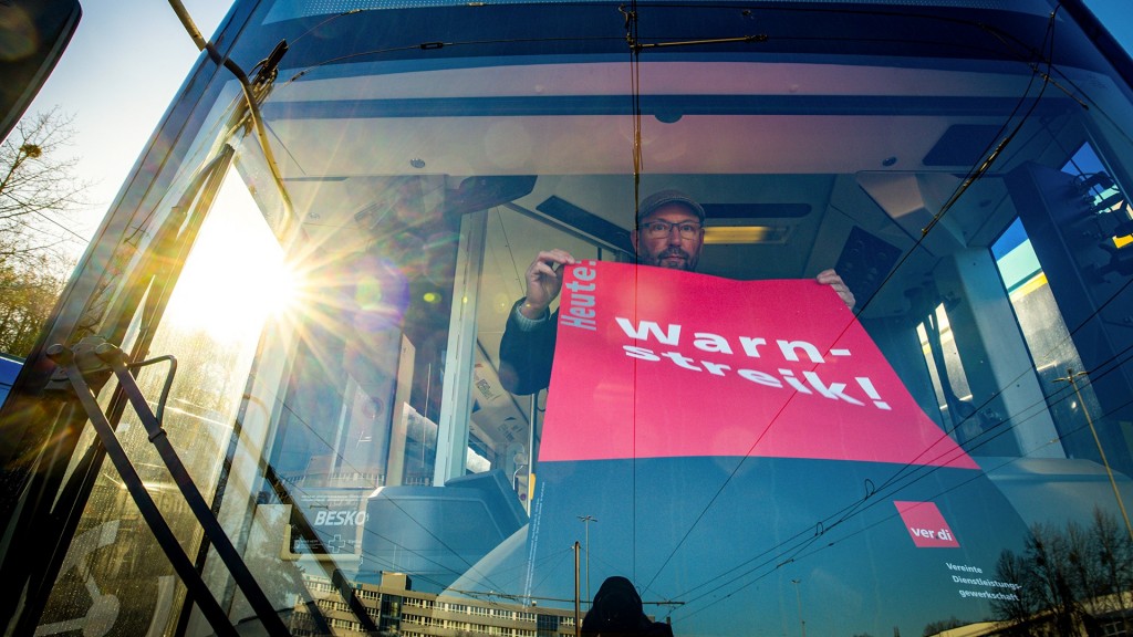 Foto: Ein Streik-Plakat der Gewerkschaft Verdi wird in die Frontscheibe eines Linienbusses gehängt