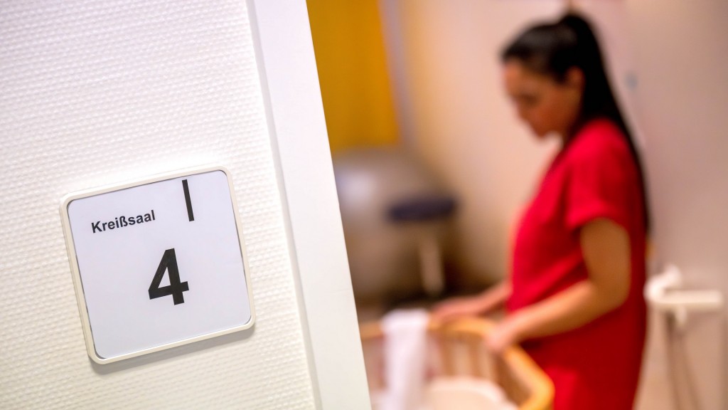 Eine Hebamme steht an einem Bett im Kreißsaal.