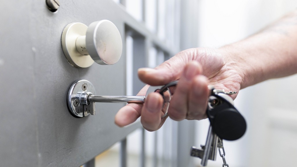 Foto: Ein Justizbeamter steckt einen Schlüssel in das Schloss einer Haftzelle.