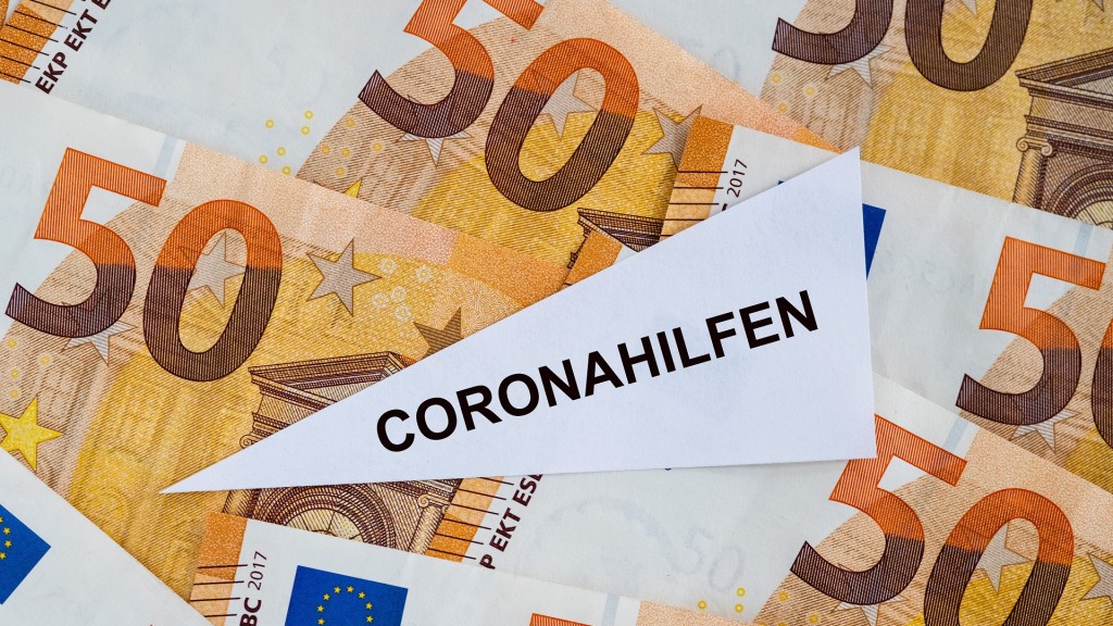 Foto: Ein Dreieck mit dem Wort Coronahilfen liegt auf mehreren 50 Euroscheinen, Symbolfoto zum Thema Coronahilfen.