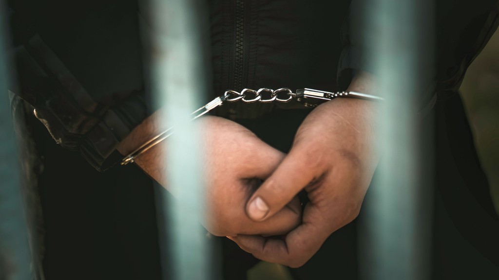 Ein Häftling in Handschellen hinter Gittern